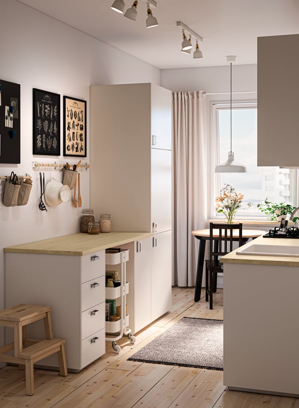 Una cocina con mesón de cocina EKBACKEN con efecto laminado de Fresno y muebles de cocina color blanco.