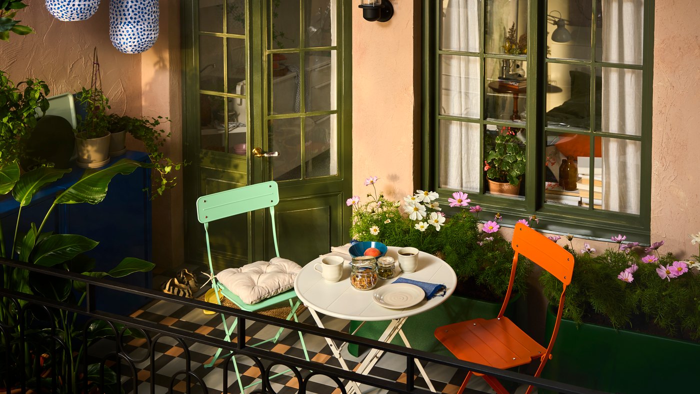Balkon met SUNDSÖ tuinmeubels in vrolijke kleuren omgeven door planten en twee SUNDSÖ kasten.