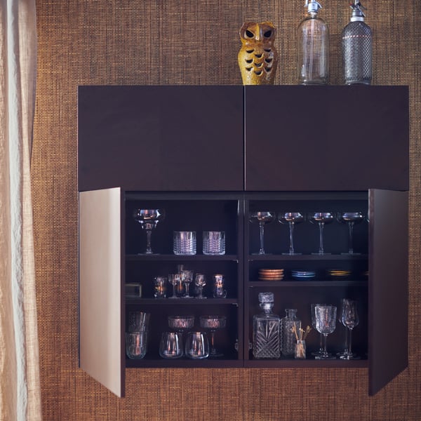 A BESTÅ wall cabinet with brown HEDEVIKEN doors, two of which are open showing glasses and cocktail-making accessories.