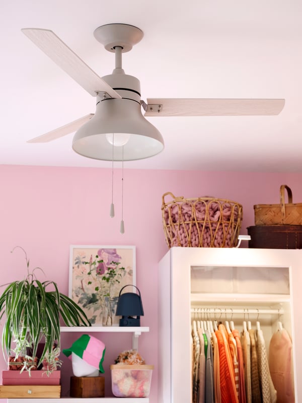 AKTERSTAGAD ceiling lamp/fan in a room with pink walls, shelves and a wardrobe in background.