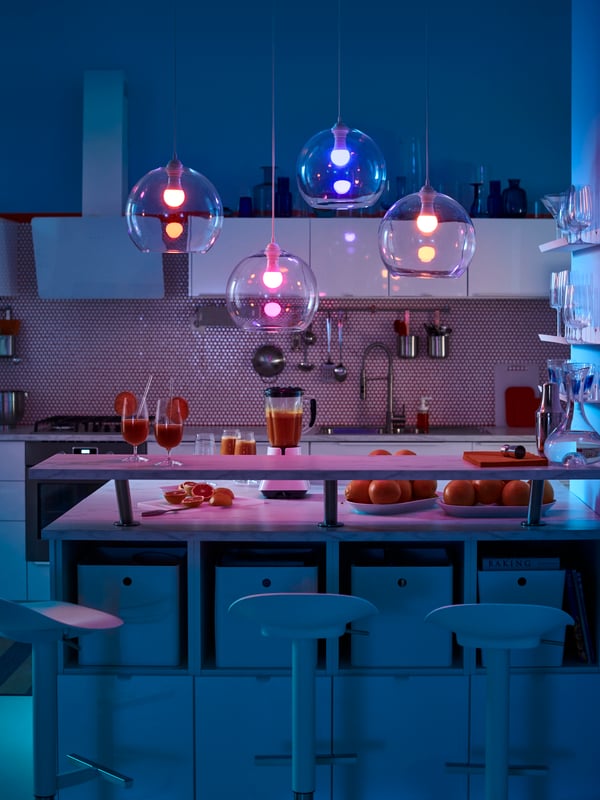 A kitchen with METOD wall cabinets, RINGHULT drawer fronts, JANINGE bar stools and TRÅDFRI LED bulbs creating coloured light.
