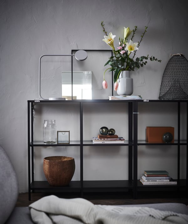 Etagères industrielles en métal noir avec divers accessoires de déco, tels que vase, panier et livres