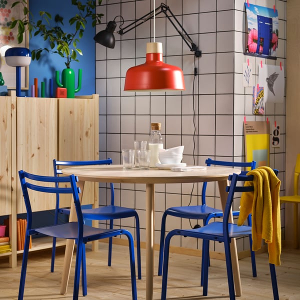 Una cocina con una mesa de madera redonda LISABO con cuatro sillas GENESÖN azules.