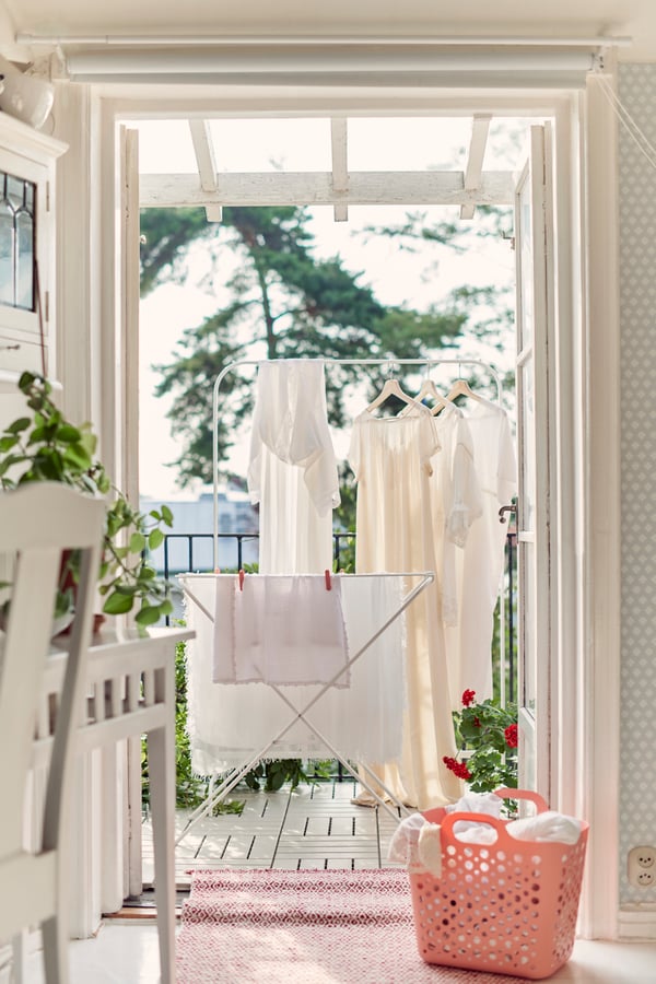 A room with an open balcony door where clothes hang to dry after washing.