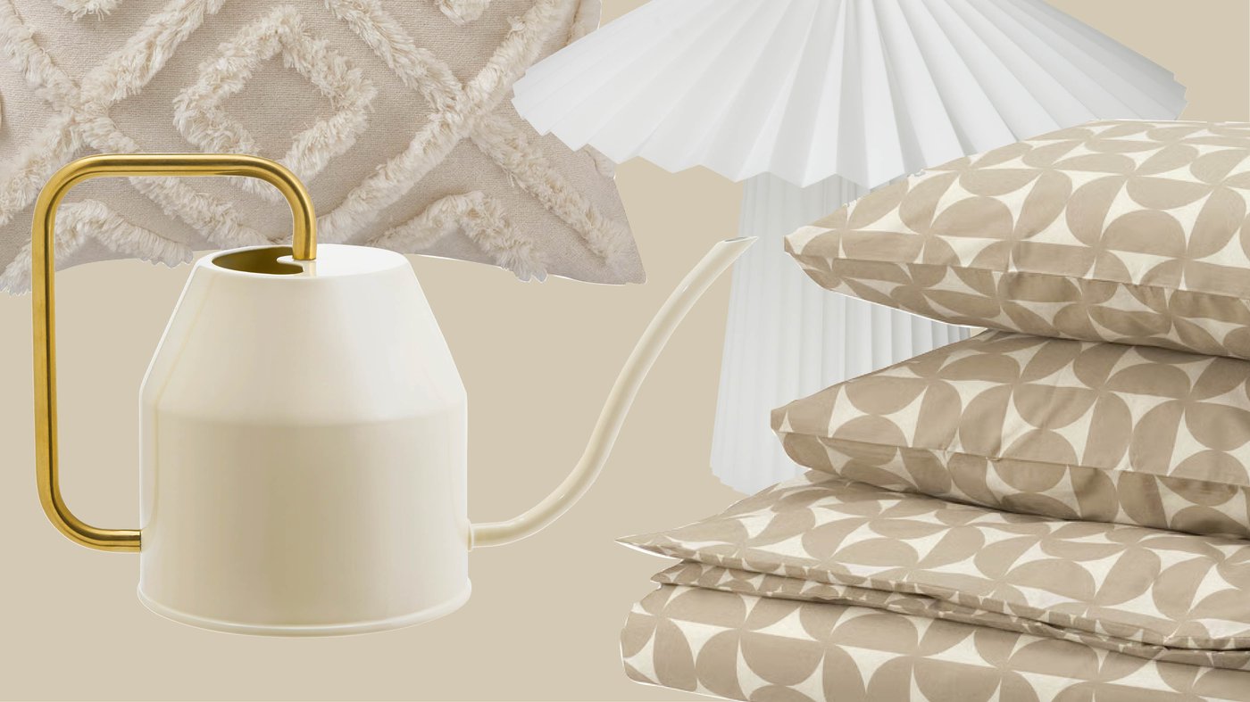 Un coussin beige texturé, une literie IKEA géométrique, une lampe plissée blanche et un arrosoir crème avec une poignée dorée s'associent pour créer une esthétique calme et élégante dans la chambre à coucher.