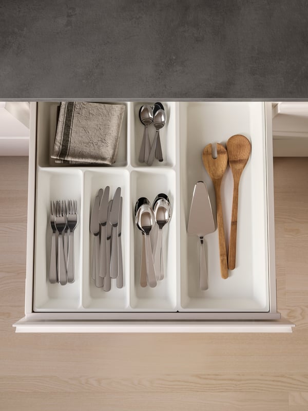 A kitchen drawer opened, revealing stainless steel cutlery in an UPPDATERA cutlery tray and utensils in a utensil tray.