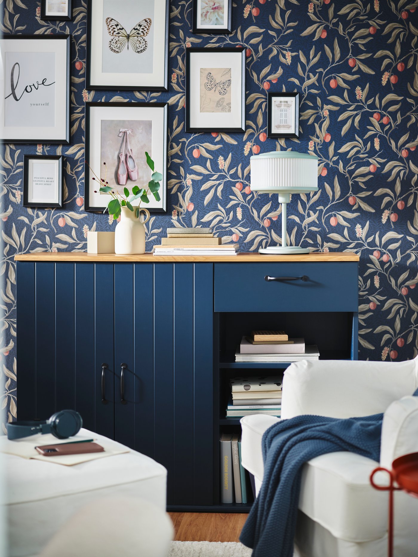 Ein blaues Sideboad aus der IKEA SKRUVBY Serie. Im Hintergrund eine Wand mit bunter Tapete und Bildern mit KNOPPÄNG Bilderrahmen.