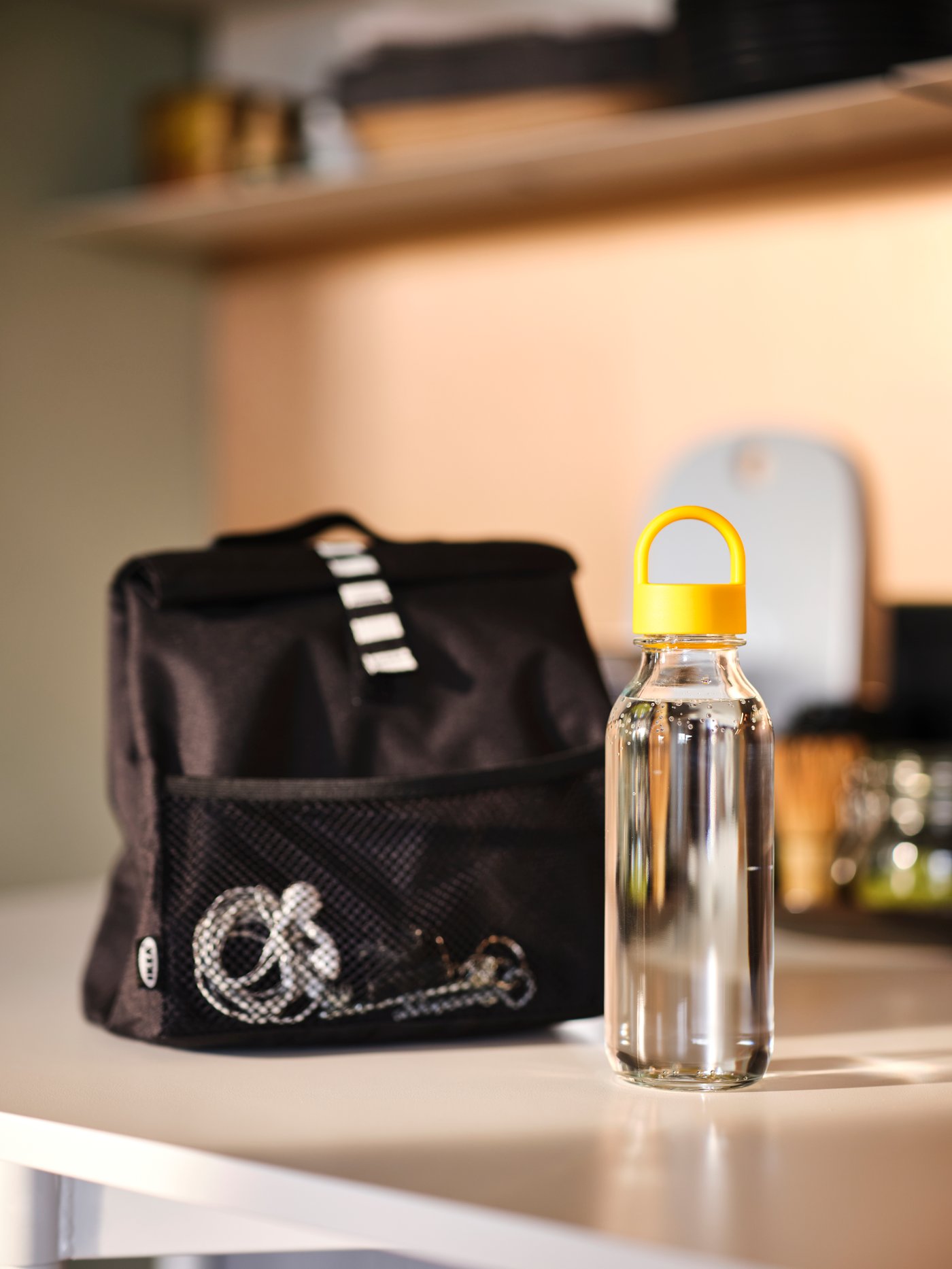 A clear glass/yellow FORMSKÖN water bottle