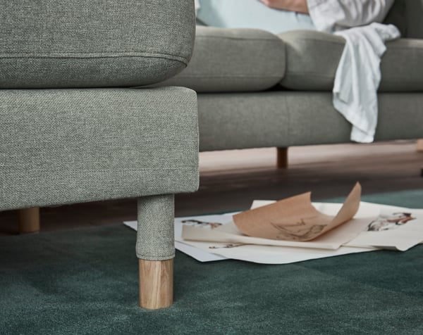 A close-up of the legs of a LANDSKRONA sofa standing on a dark green rug.