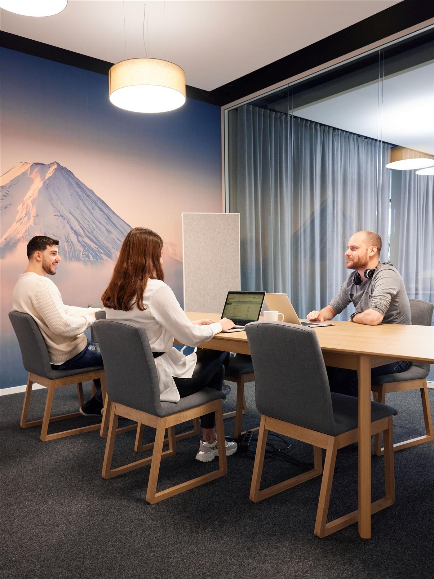 Drei Personen sitzen in einem Konferenzraum an einem Schreibtisch