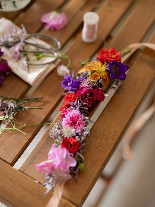 Handgemaakte bloemenkrans met wilde bloemen op een IKEA TÄRNÖ tuintafel tijdens Midsommar.