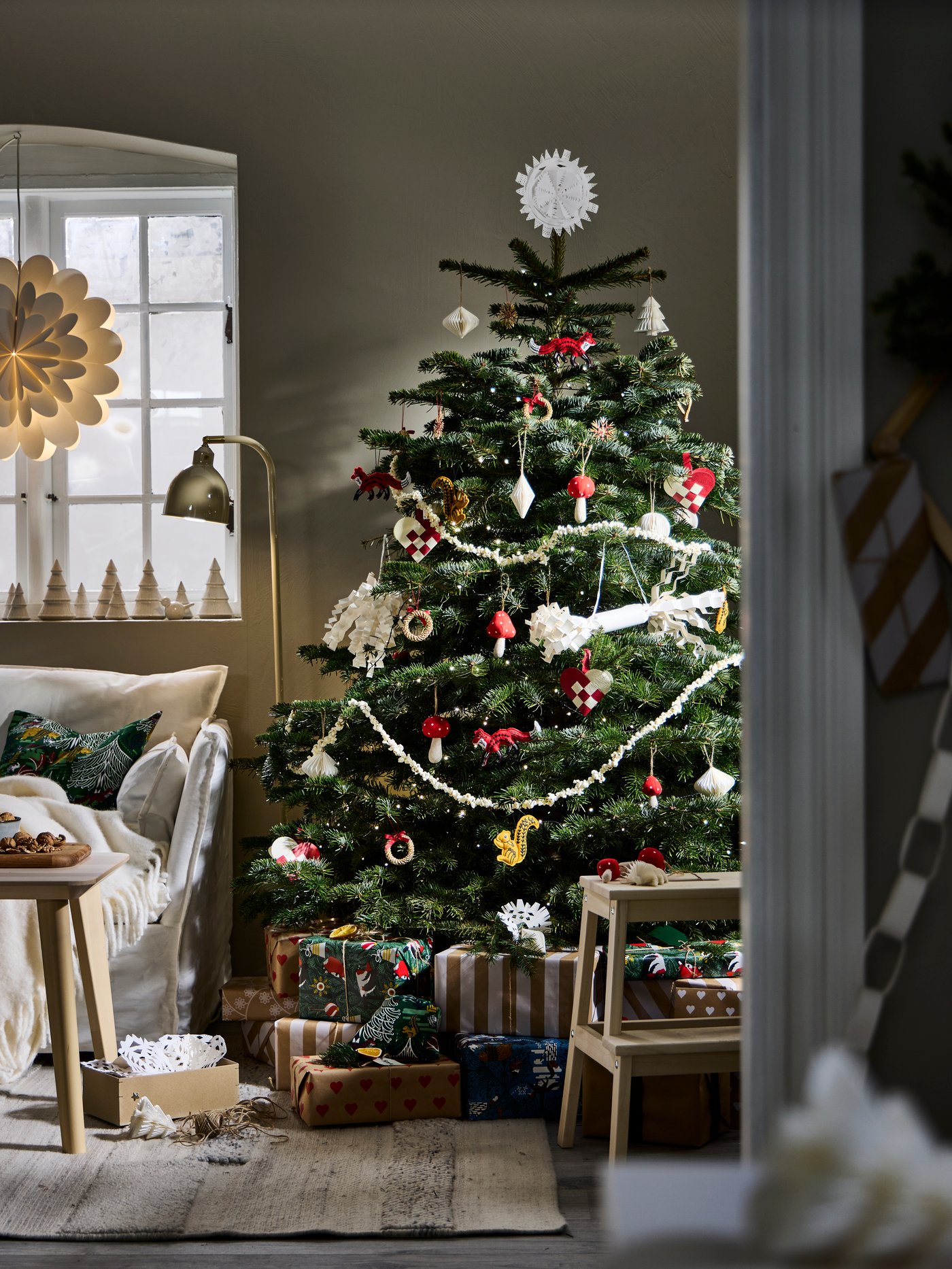 Rustic Christmas tree in corner of Scandinavian living room decorated with variety of VINTERFINT tree ornaments.