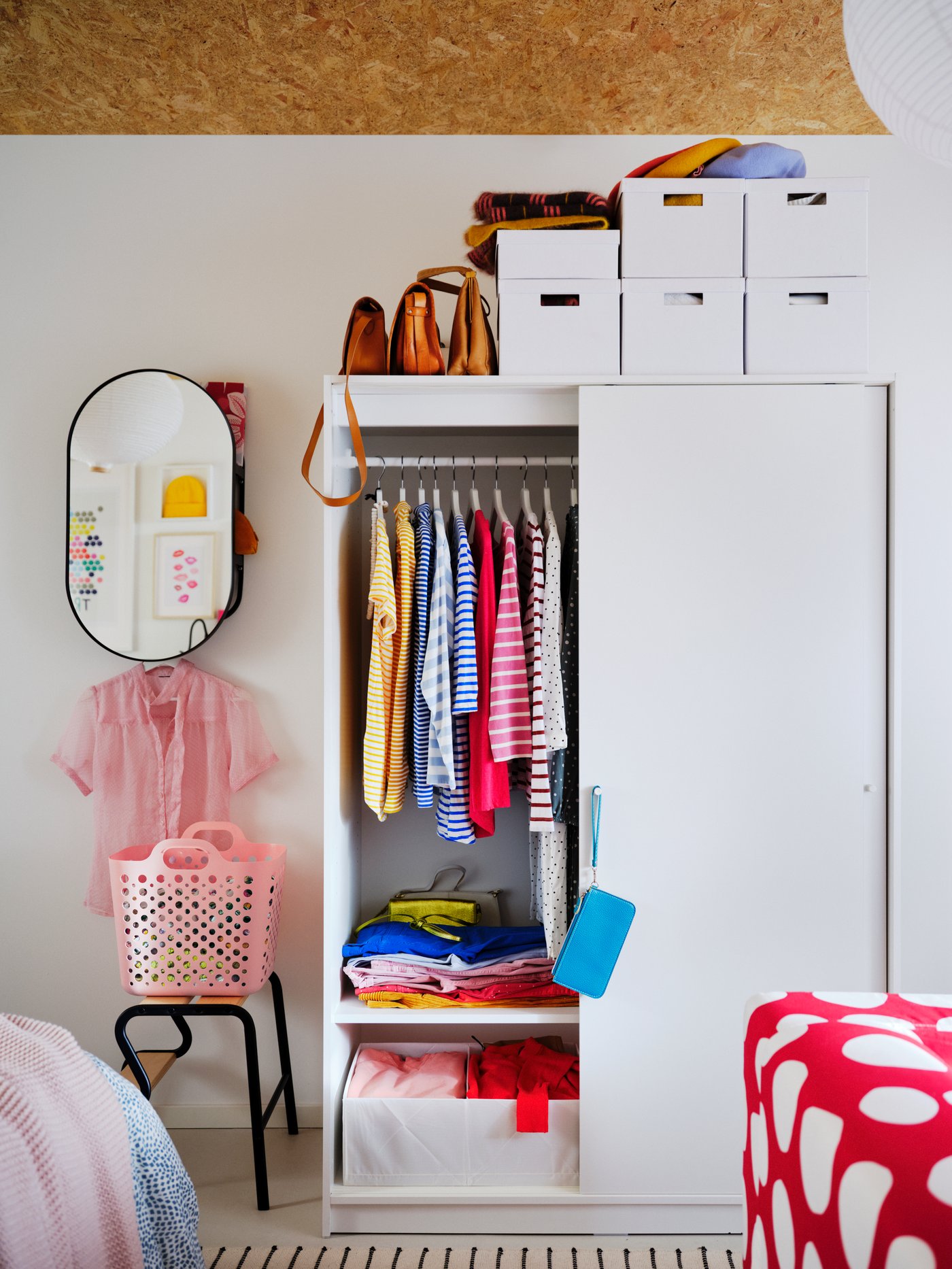 A white KLEPPSTAD sliding-door wardrobe, half open to reveal colourful clothing, with white storage boxes on top.