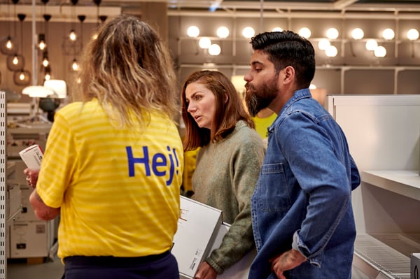 Una colaboradora IKEA atendiendo a una pareja de clientes.