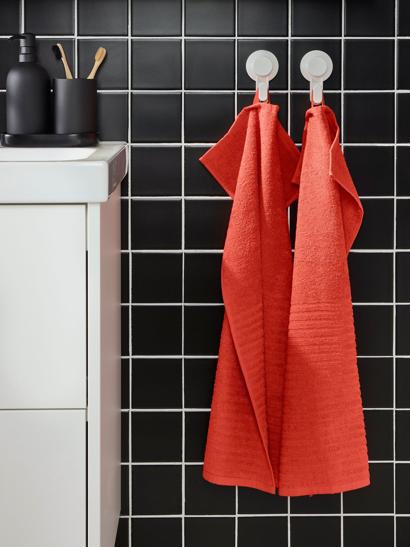 Toalla de mano VÅGSJÖN color rojo anaranjado en un baño.