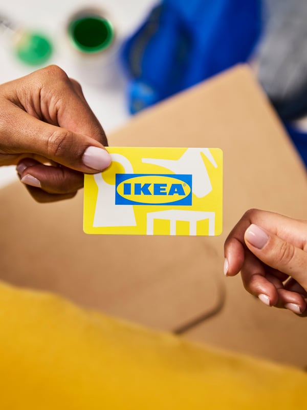 Twee handen houden een IKEA-cadeaubon vast.