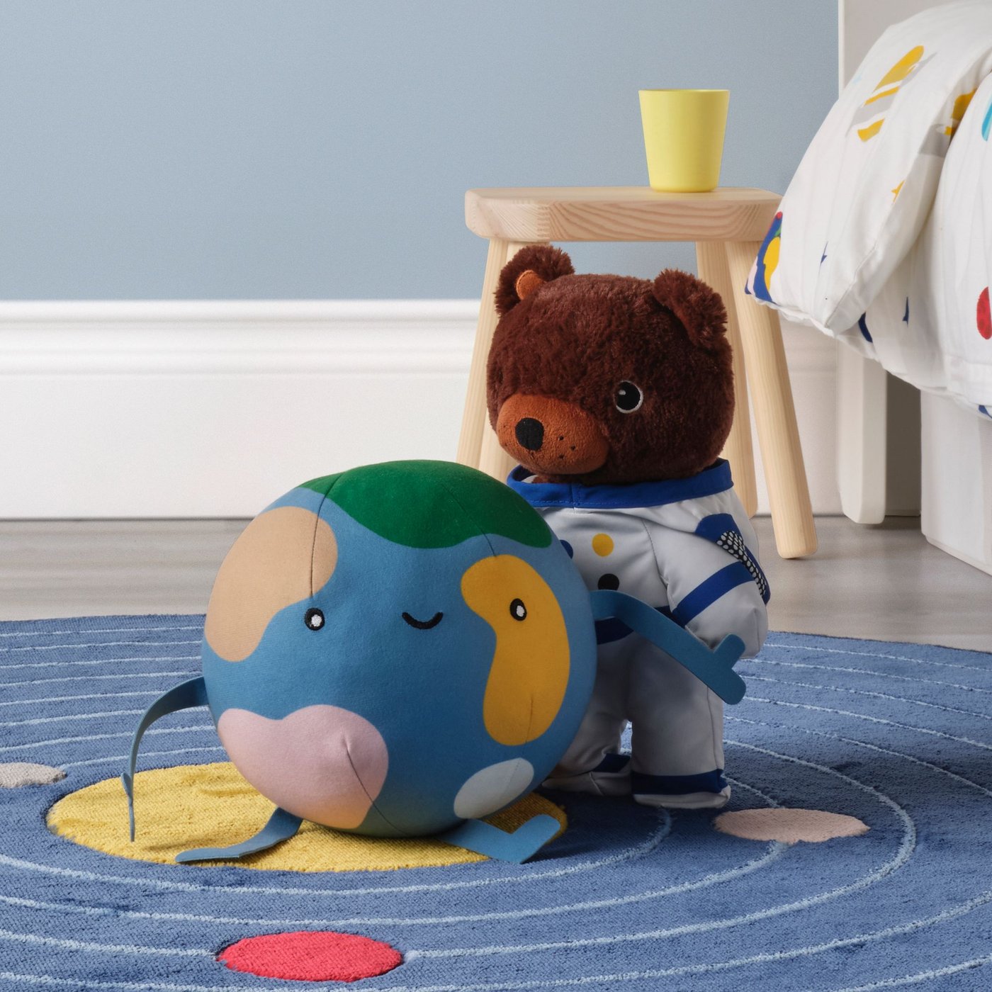 Un mundo de peluche y un oso de peluche astronauta sobre una alfombra de sistema solar.