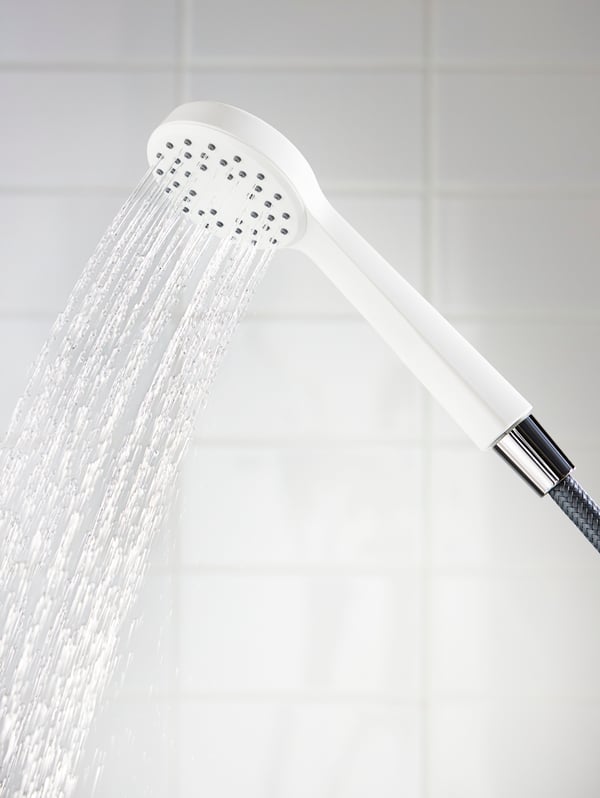 Cabezal de ducha LILLREVET blanco con regulador de caudal con el agua corriendo. 
