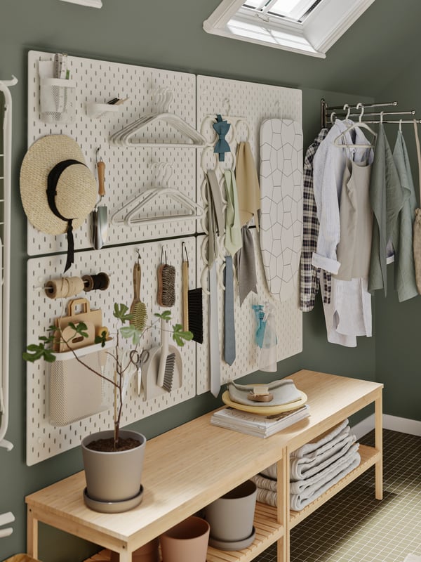 Tres grandes tableros SKÅDIS en un dormitorio con diferentes ganchos ordenando ropa y accesorios.