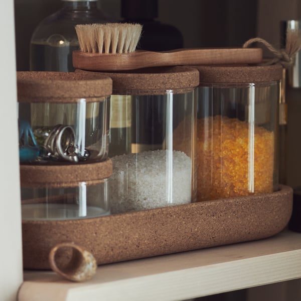 Des pots pour salle de bain avec des contenus différents et une brosse en bois dessus.