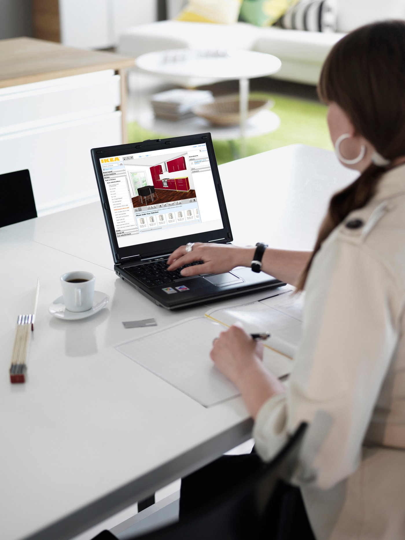 You see a woman with one hand on her laptop, designing a kitchen in the IKEA kitchen planner.