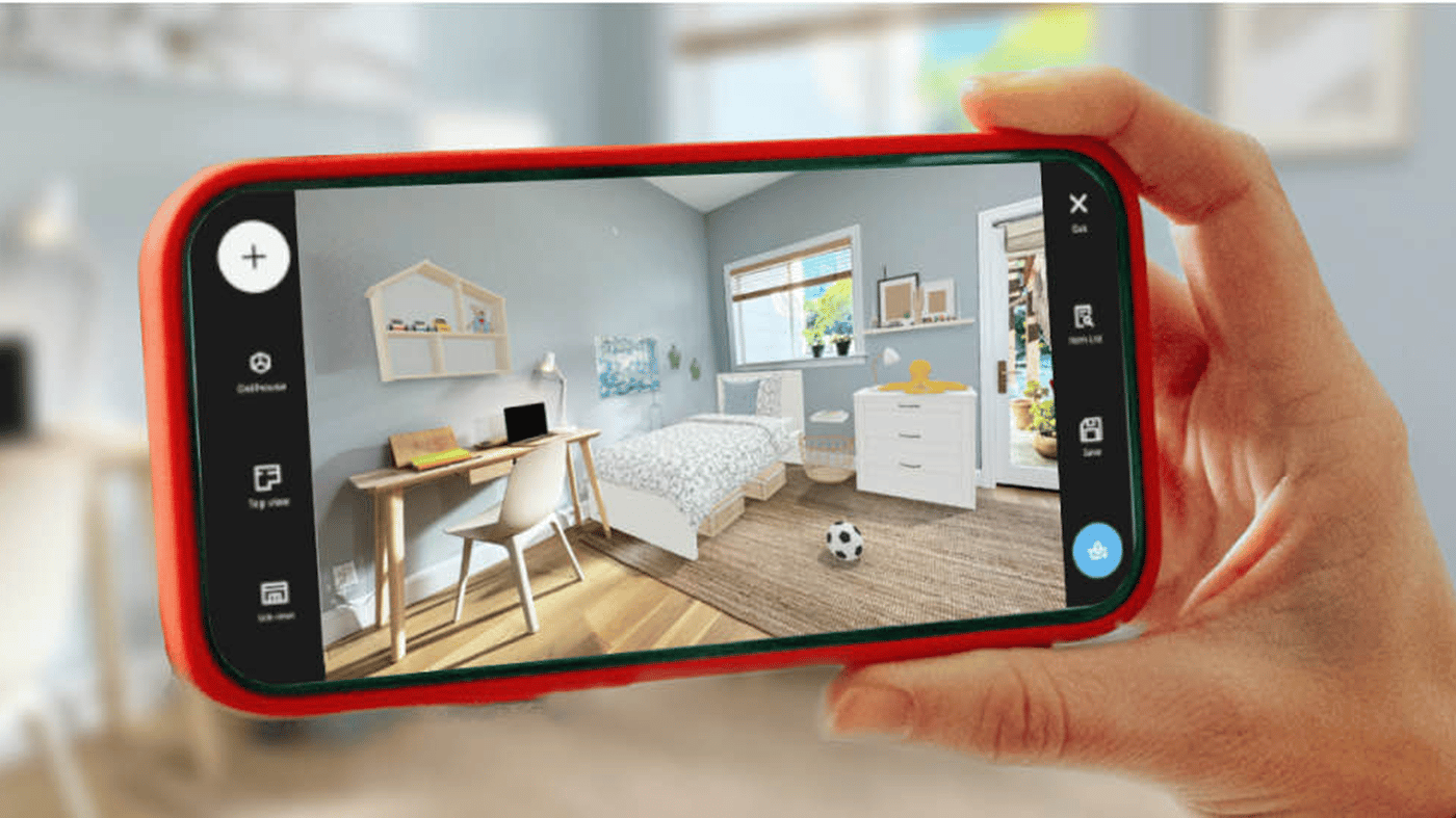 A hand holds a smartphone showing an IKEA app 3D kids room plan with bed, desk, storage and wooden floor.