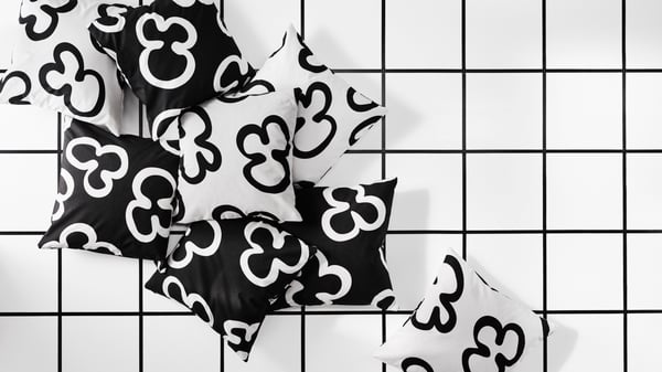 Eight cushions with black and white KLIPPBRÄCKA cushion covers are placed on a floor. The cushions are seen from above.