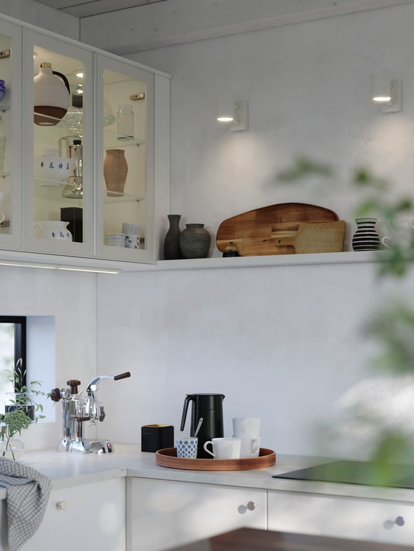 A bright kitchen has white glossy RINGHULT kitchen cabinet doors and wall cabinets with HEJSTA glass doors, and a white wall shelf.