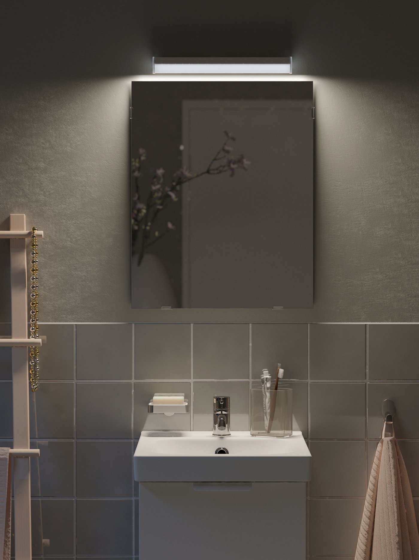 A wash-basin on a cabinet with a pink towel by it, with a LÄRBRO mirror above it with an LED lighting strip at the top.