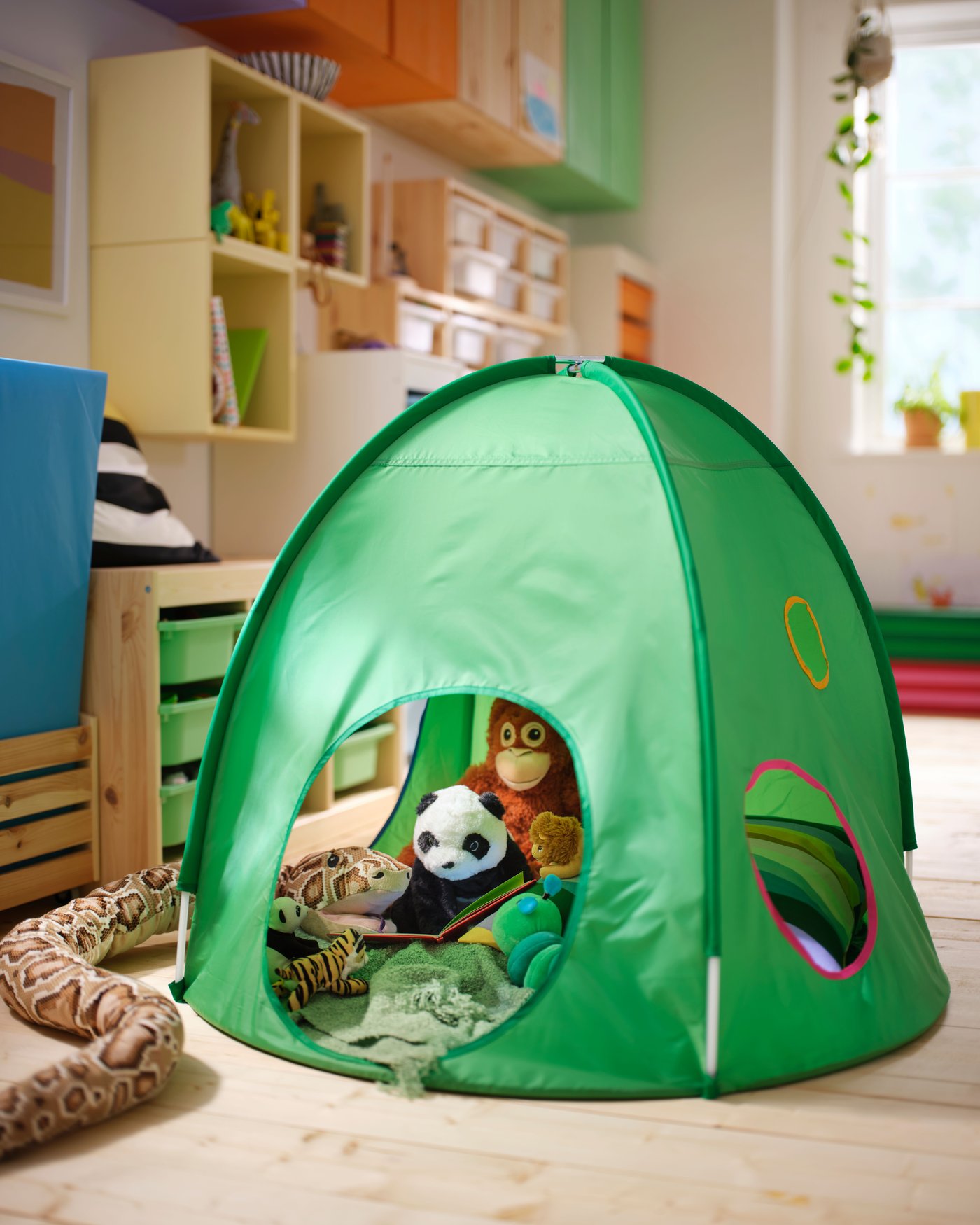 A green DVARGMAS play tent filled with various animal soft toys in the kids’ room.