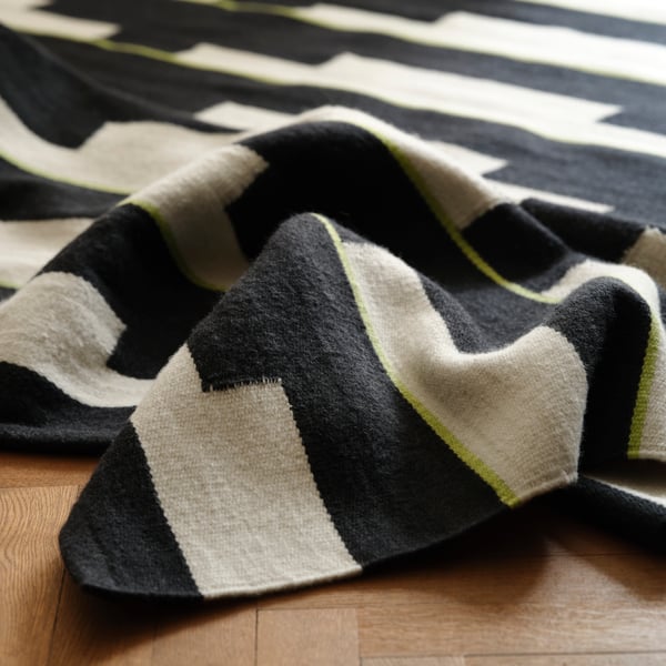 A black/white/light green handwoven STOCKHOLM 2025 rug, flatwoven