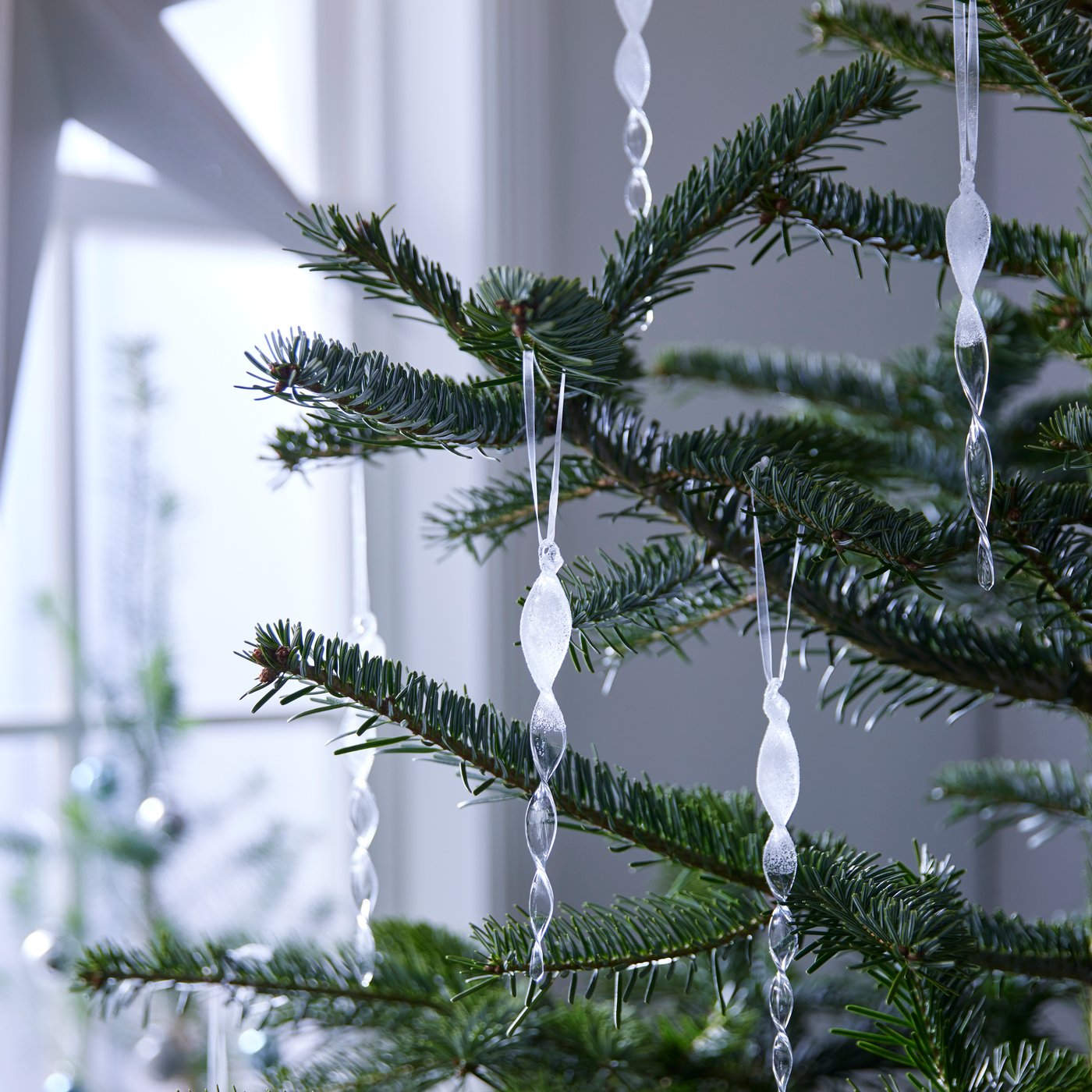 Julgran med transparenta hängande dekorationer.