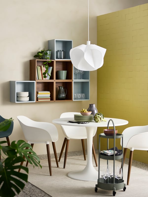 A compact room with wall-mounted EKET shelving units in the background and a white DOCKSTA table and GRÖNSTA chairs in front.