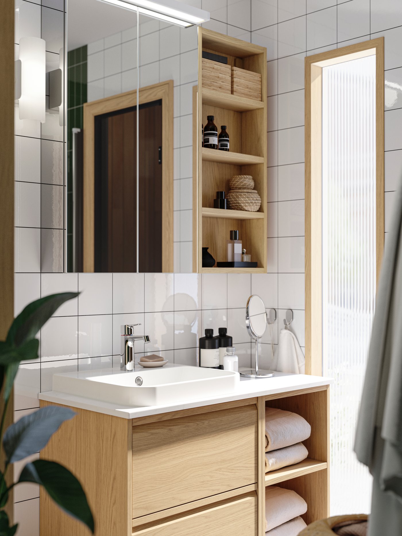 An ÄNGSJÖN washstand with drawers in oak effect is in a white bathroom with a LETTAN mirror cabinet with doors above it.
