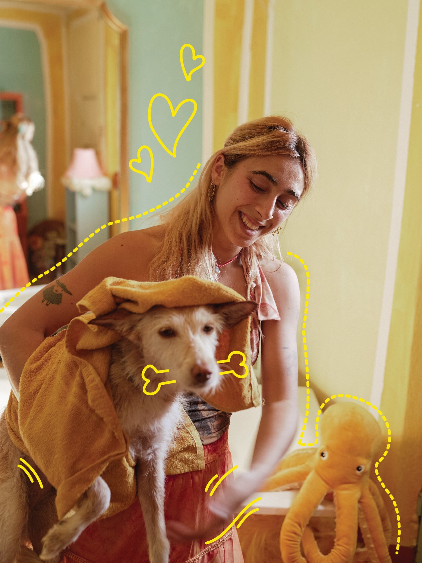 A woman drying her dog with a yellow towel after a wash.