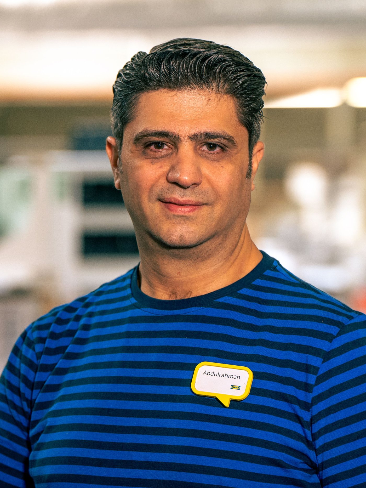 Abdul stoji u robnoj kući IKEA u plavoj radnoj uniformi.