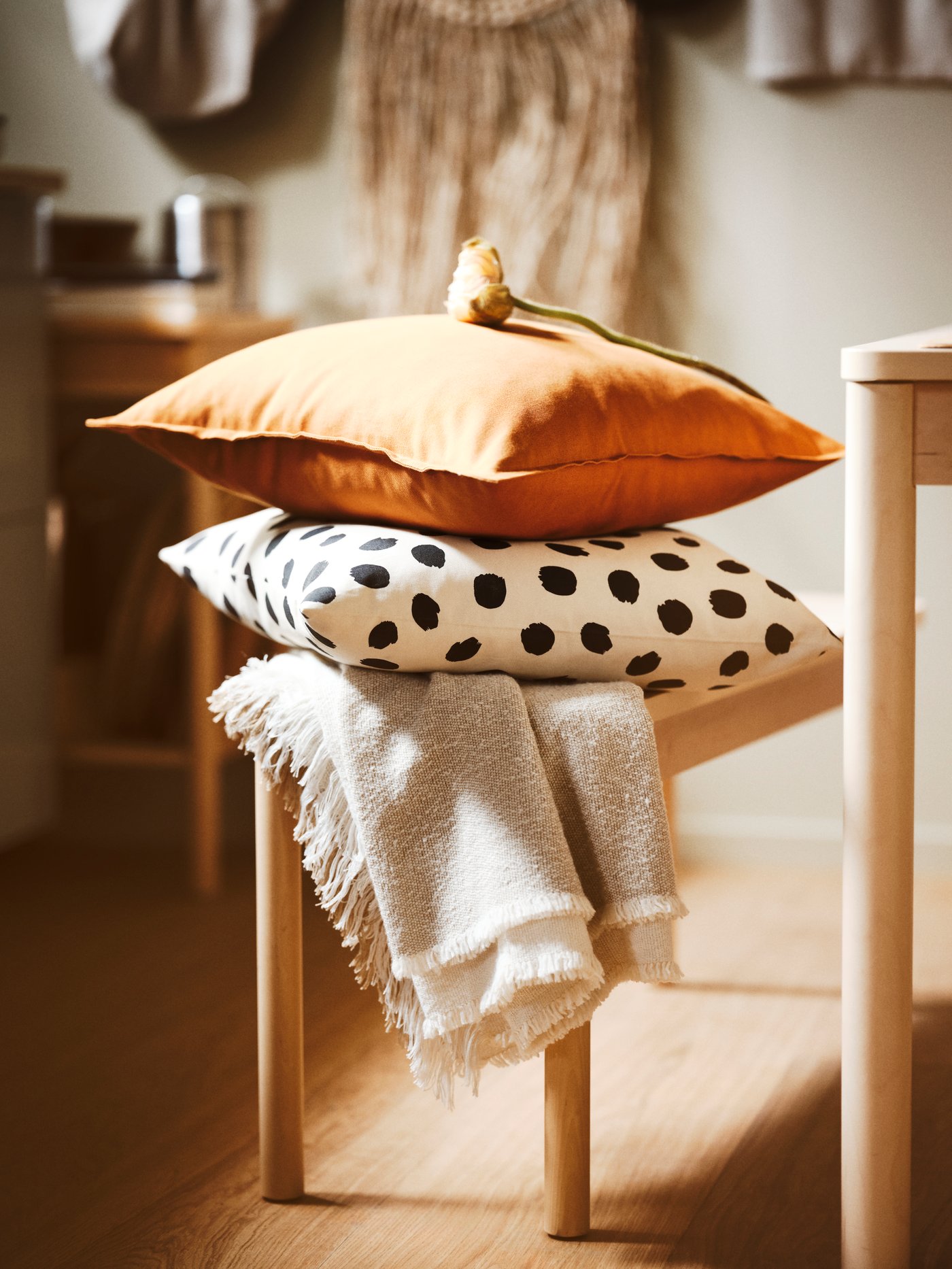 A bench with a throw and two cushions dressed in a GURLI cushion cover and a ODDNY cushion cover with dotted pattern.