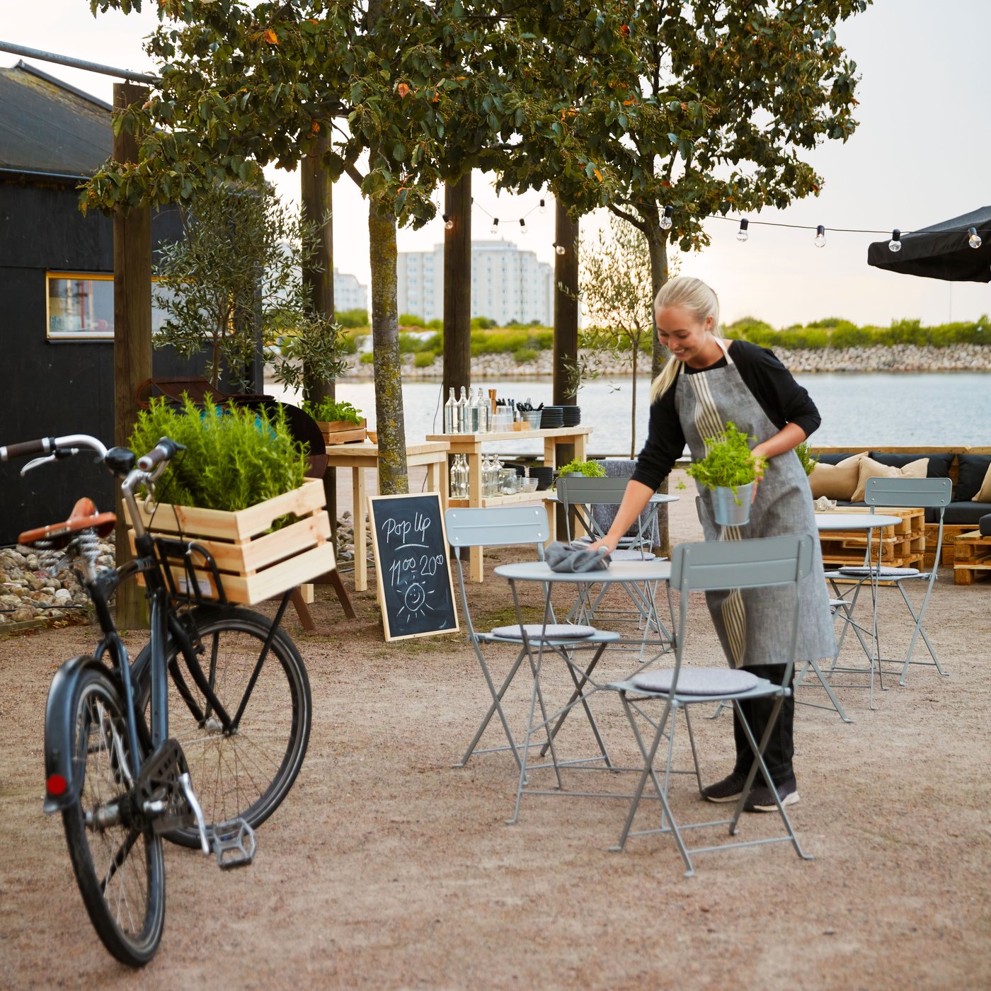 A person cleans a grey SUNDSÖ table on a patio with a cleaning cloth.