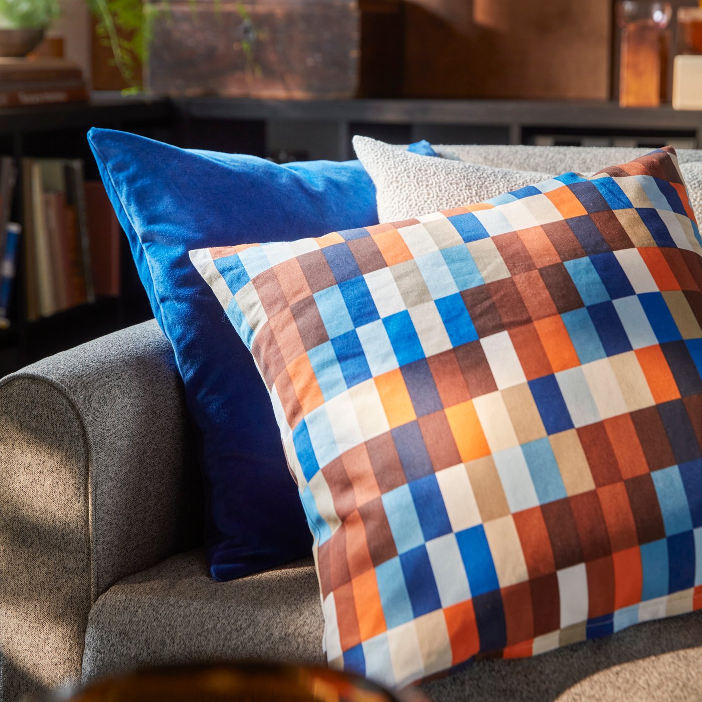 A close-up of a SALTMYRAN 3-seat sofa with a brown/blue LÖVNATURSKOG cushion cover and two other cushions.