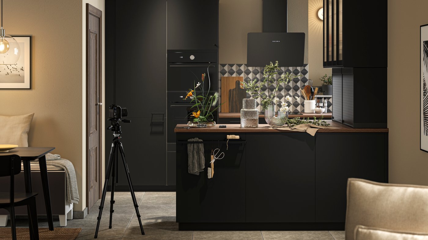 Cuisine belge moderne avec des armoires noires, un comptoir en bois foncé, un mur de carreaux géométriques noirs et blancs, des éléments décoratifs sur le comptoir et un appareil photo sur un trépied dirigé vers la cuisine ; À gauche, une table à manger avec des chaises, à droite, un canapé beige.
