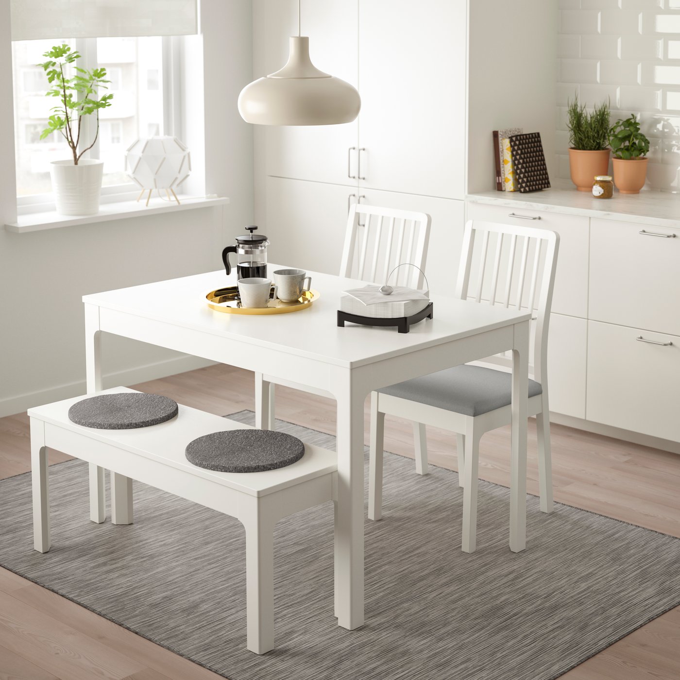 EKEDALEN extendable dining table in white with 2 chairs and a bench in a diing room area with a ceiling pendant lamp hanging above it.