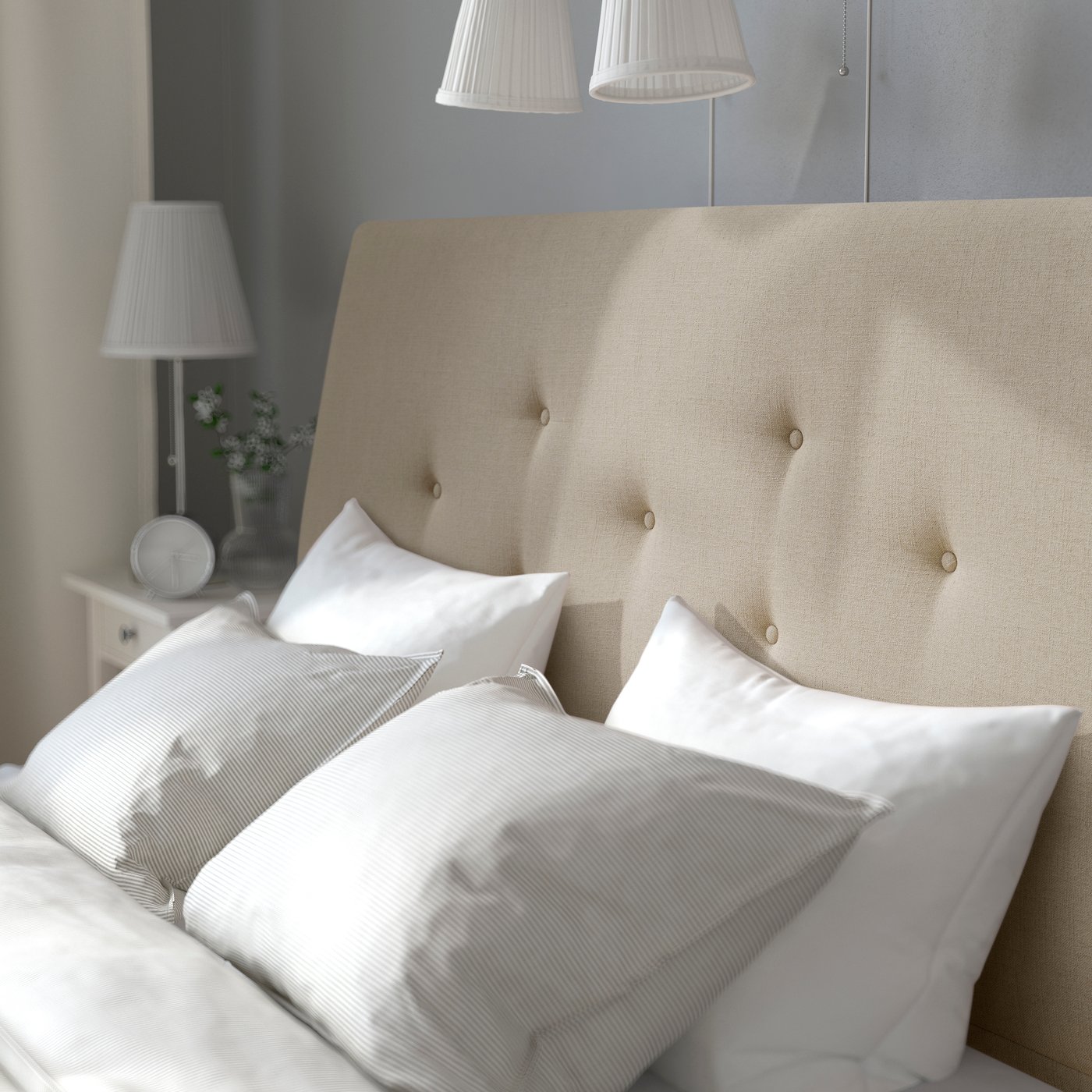 Nahaufnahme eines gepolsterten IDANÄS Bettgestells mit Kissen in Naggen Beige