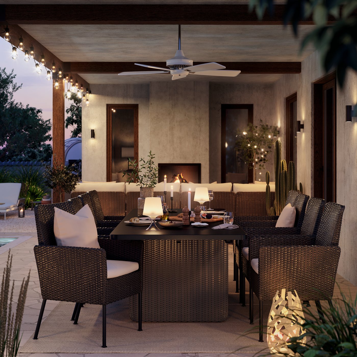An outdoor dining setup in evening light, featuring six dark grey VITTSKÄR dining chairs with pillows and a matching table.