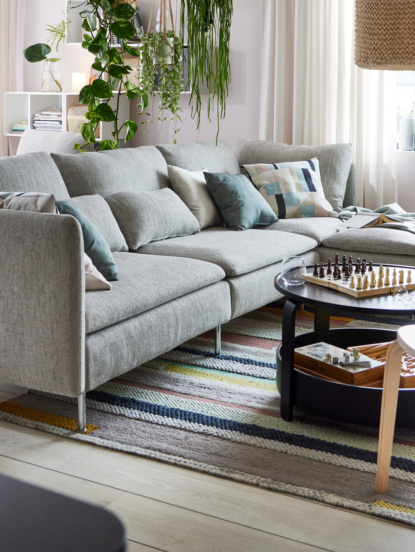Un sofá SÖDERHAMN gris con cojines decorativos encima y frente a una mesa de centro.