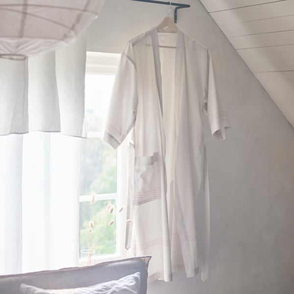 Rideaux en lin blanc et peignoir accrochés à une tringle à rideau noire
