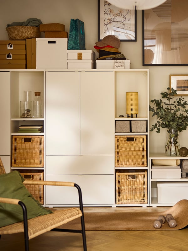 A white VIHALS TV/storage combination with many items on its shelves including KOMPLEMENT boxes and BRANÄS baskets.