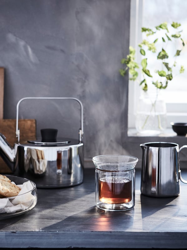 Una mesa de cocina con teteras, lecheros y una cafetera.