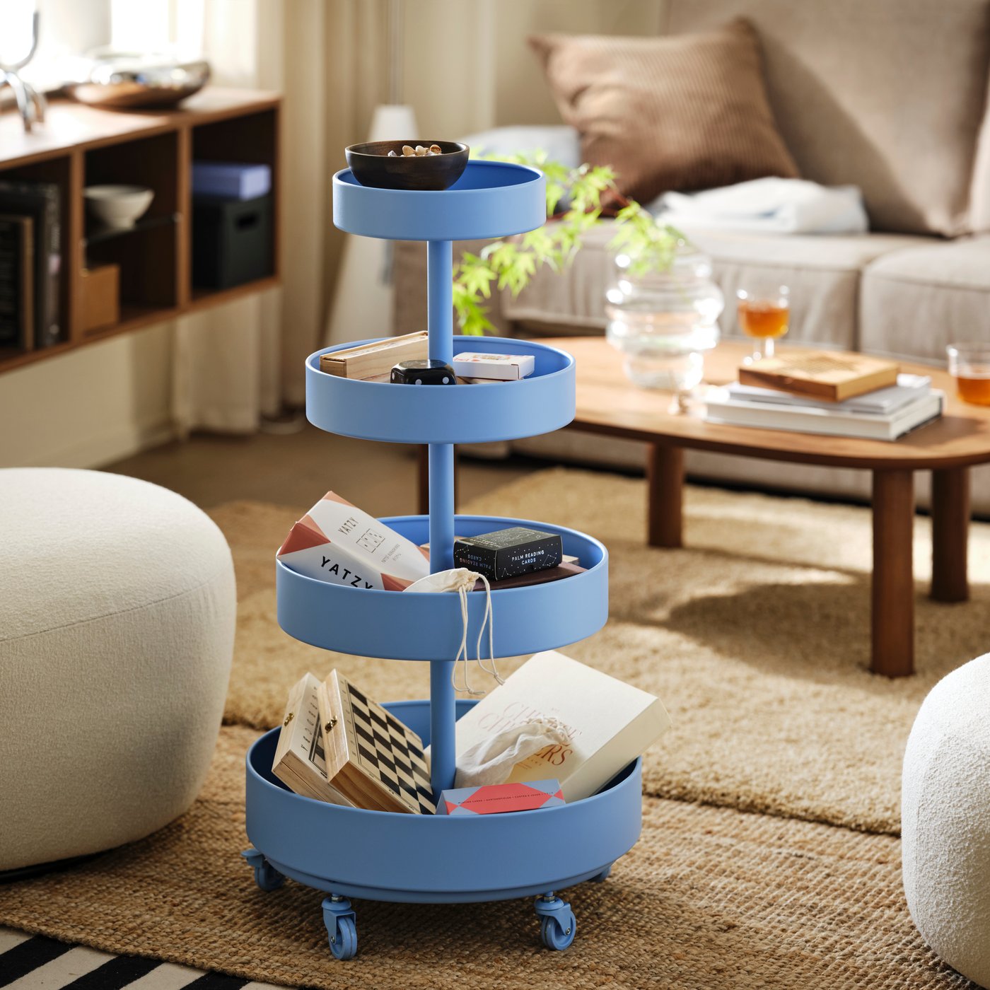 An IKEA PS 2026 trolley holding games and other small items beside a seating area.
