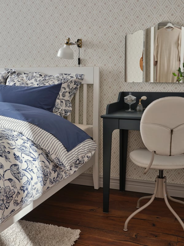 A RANARP wall clamp spotlight illuminating an IDANÄS bed, covered in a patterned duvet cover.