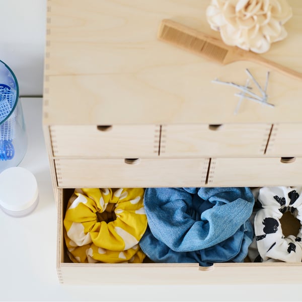 A birch plywood MOPPE minni chest with the bottom drawers open showing three rows of different coloured hair scrunchies.